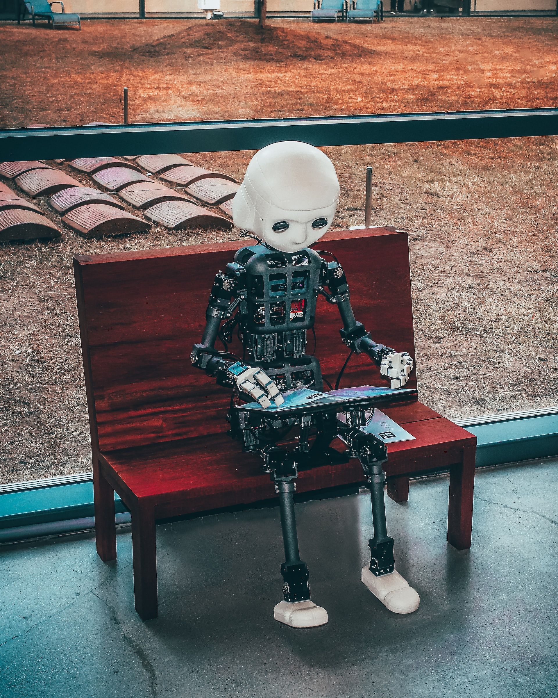Un niño robot sentado en un banco lee un libro