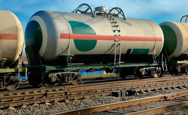 bidón gigante de petróleo sobre unas vías del tren